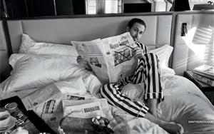 Jaunty Ryan Gosling posing for camera while reading newspaper